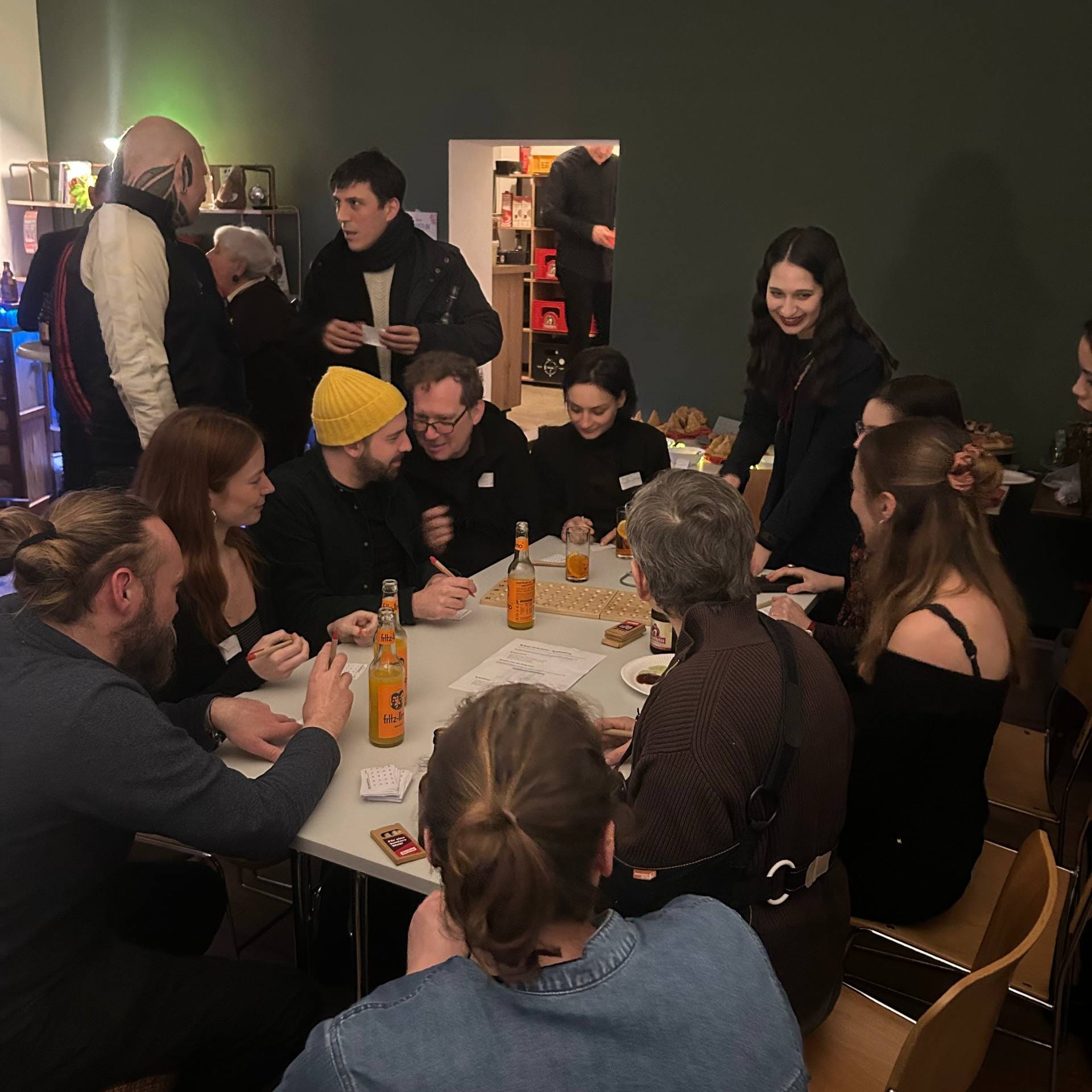 Eine Gruppe von Menschen sitzen und stehen um einen Tisch im Wahlkreisbüro und reden miteinander