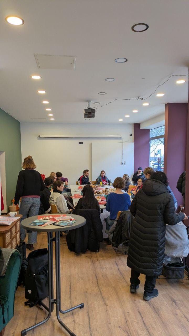 Viele Menschen sitzen zusammen an einem großen Tisch im Wahlkreisbüro und essen gemeinsam.